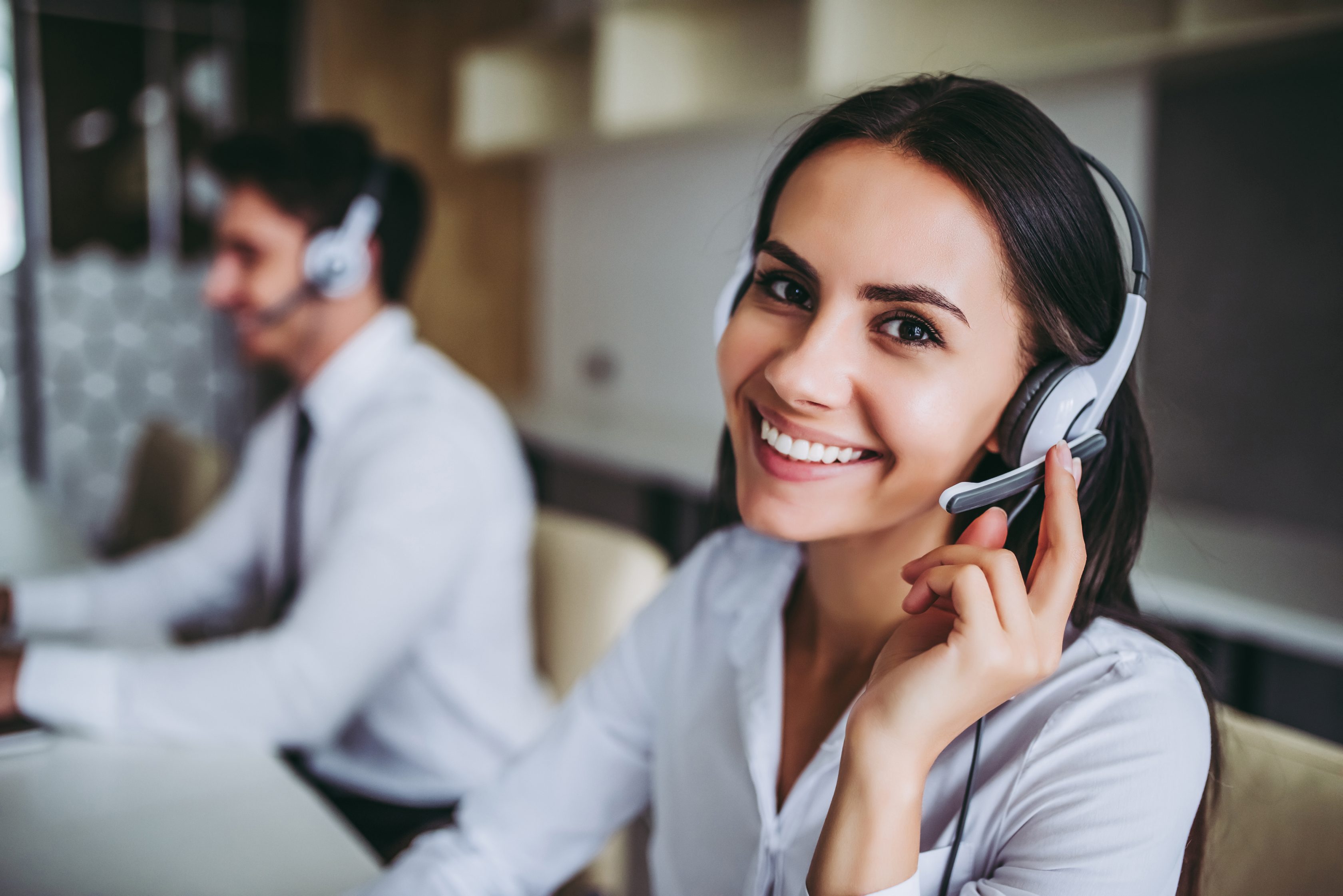 Πως μπορώ να βοηθήσω; Όμορφοι εργαζόμενοι στο κέντρο εξυπηρέτησης πελατών με ακουστικά δουλεύουν σε μοντέρνο γραφείο