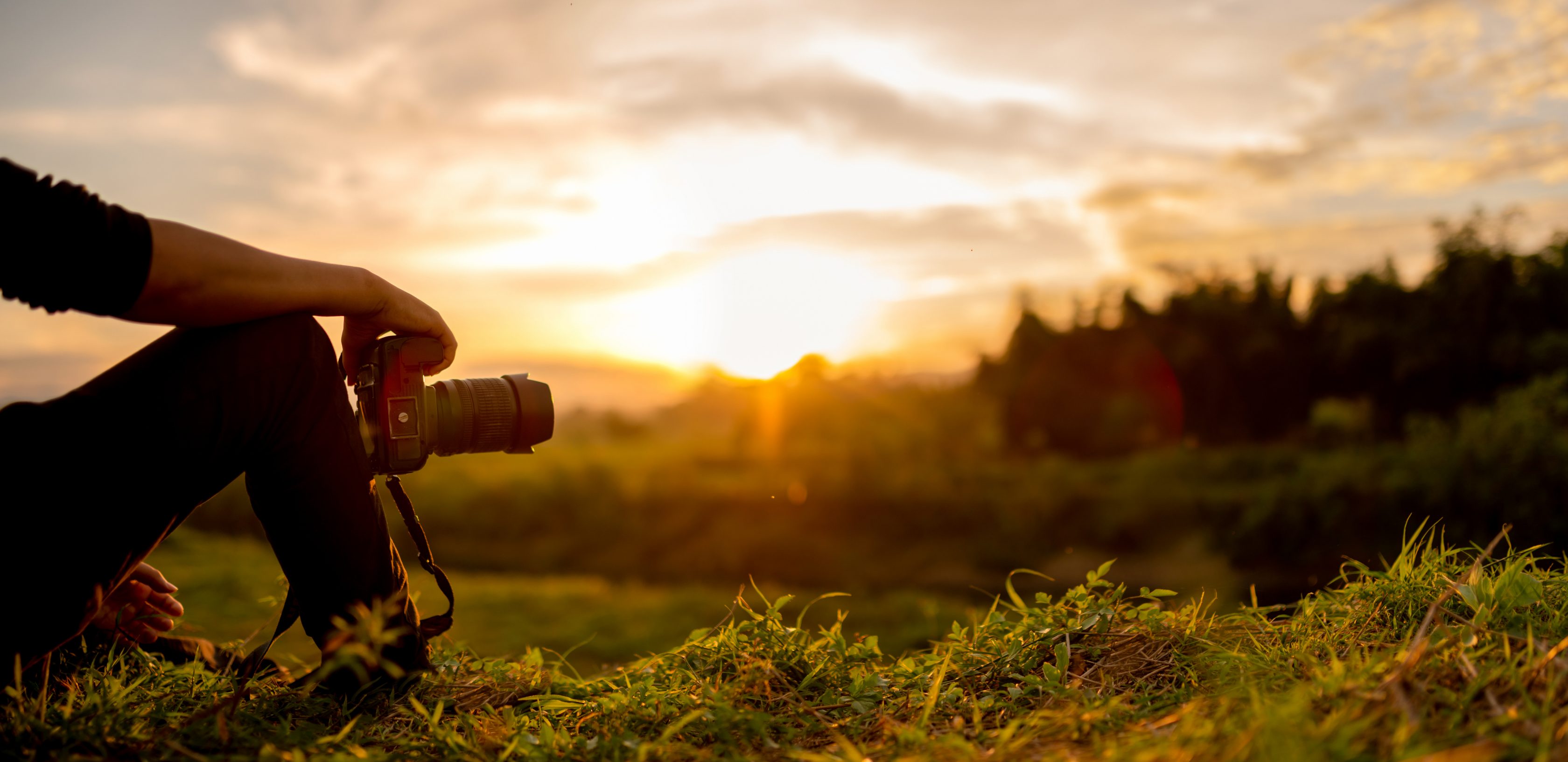 Ένας φωτογράφος κάθεται σε έναν βράχο θαυμάζοντας την φύση και το ηλιοβασίλεμα