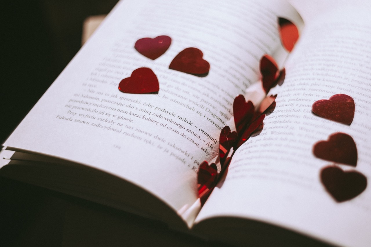 Κόκκινες καρδιές μέσα ανοιχτό βιβλίο πάνω σε ένα τραπέζι.