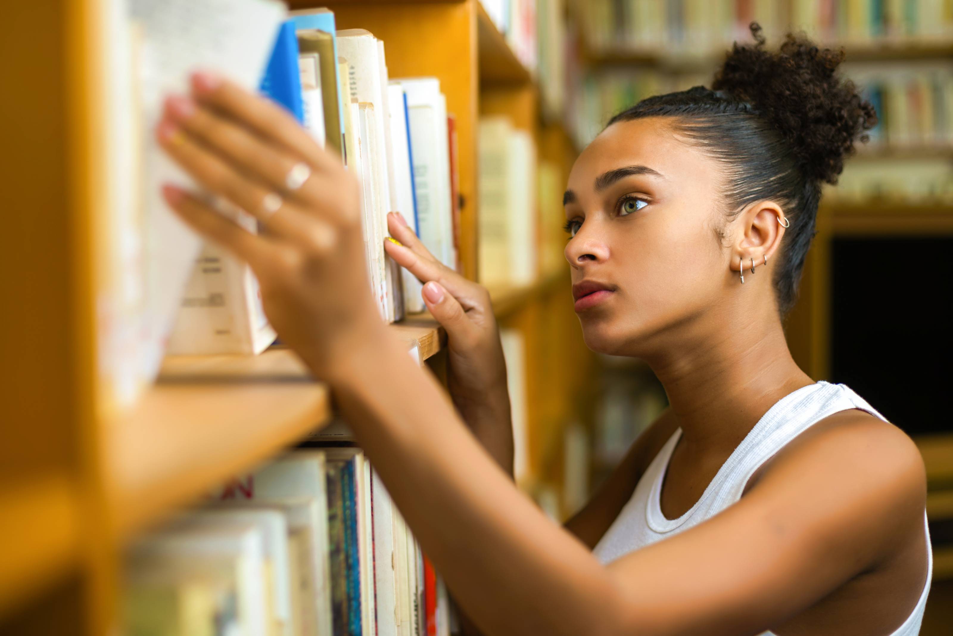 Αφροαμερικανή φοιτήτρια σε βιβλιοθήκη πανεπιστημίου ψάχνει βιβλία