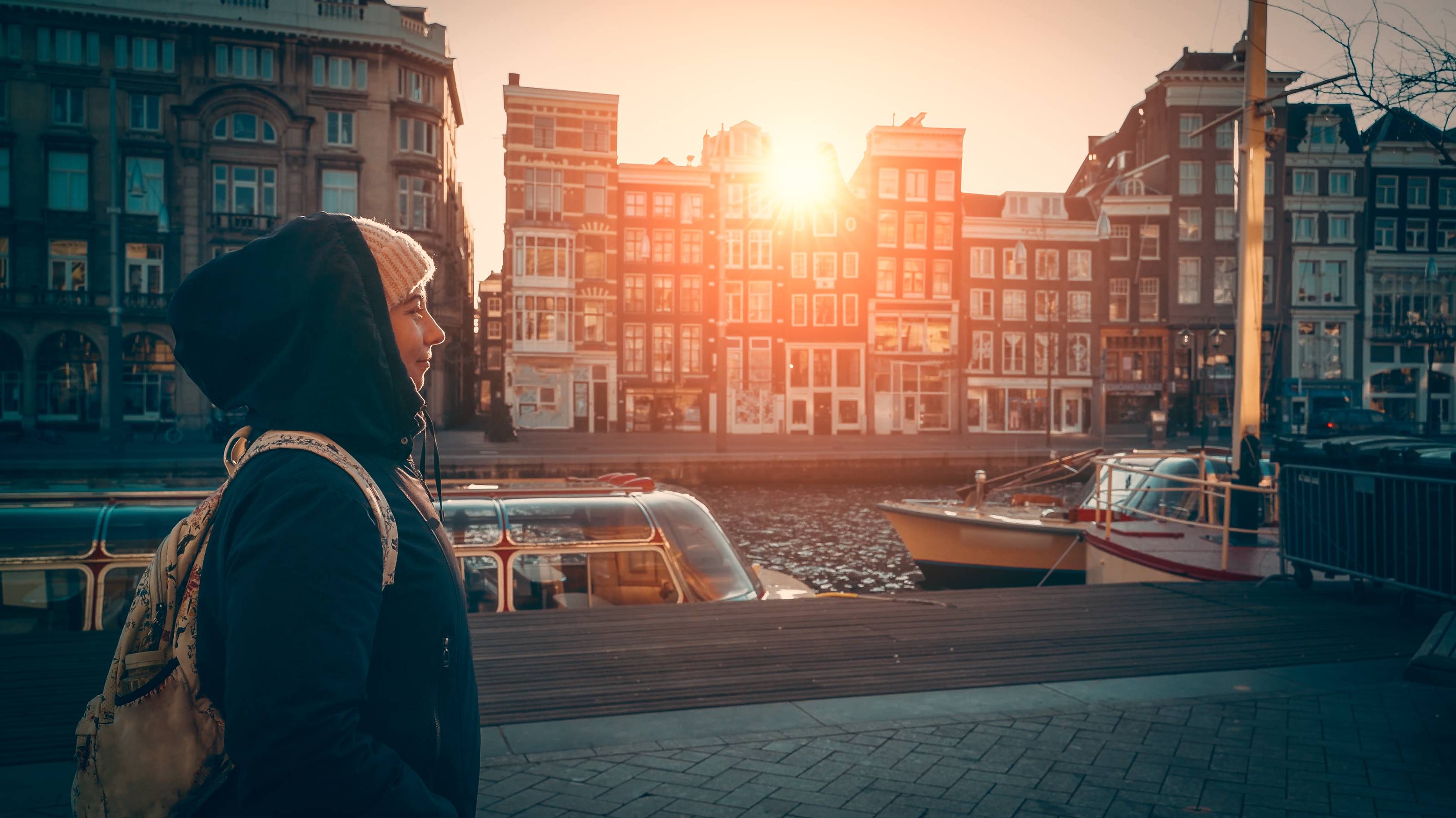Νεαρή κοπέλα περπατά κατά μήκος ενός καναλιού στο Άμστερνταμ της Ολλανδίας κατά το ηλιοβασίλεμα 