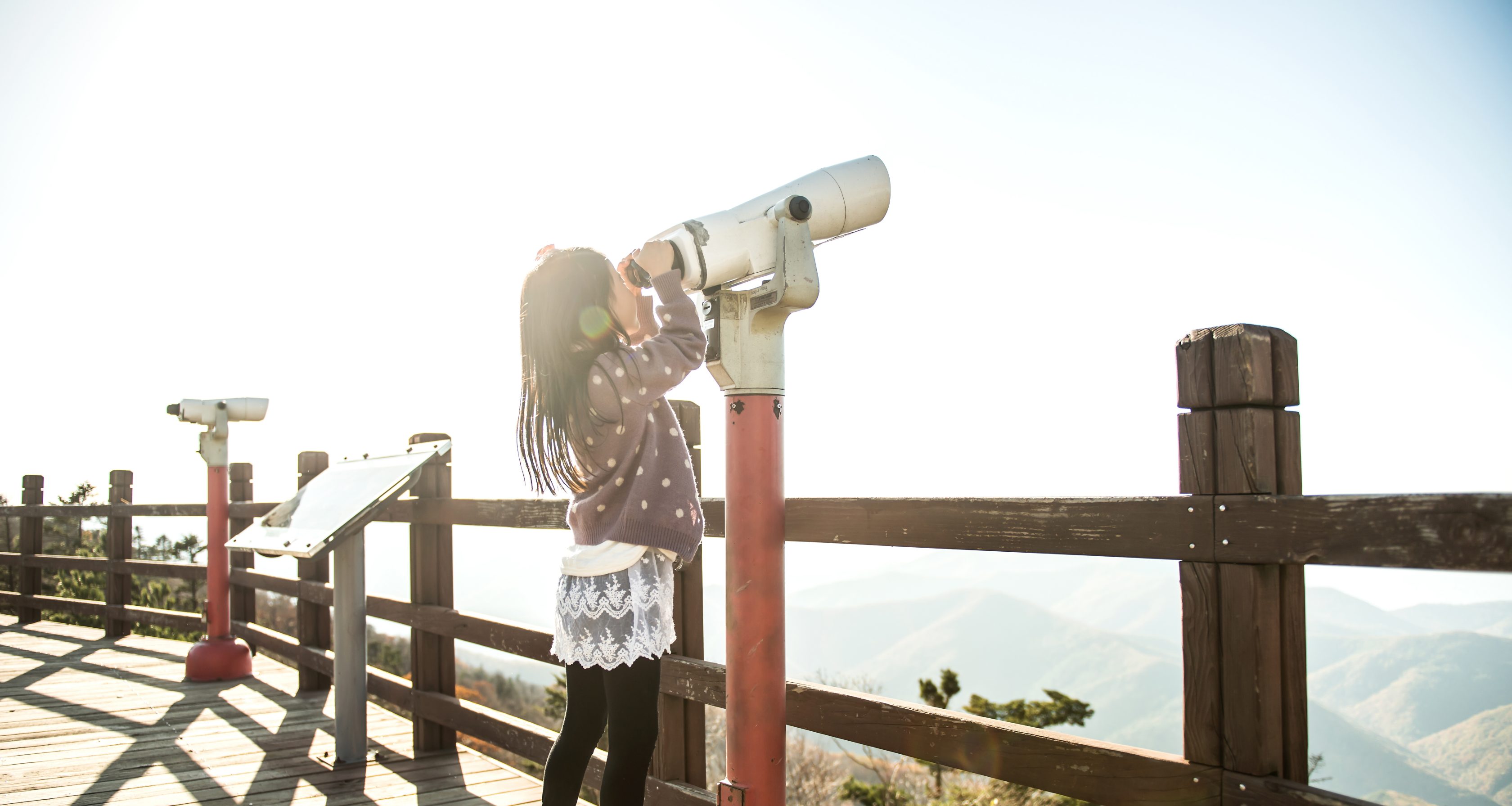 A little girl observing the sky with a telescope