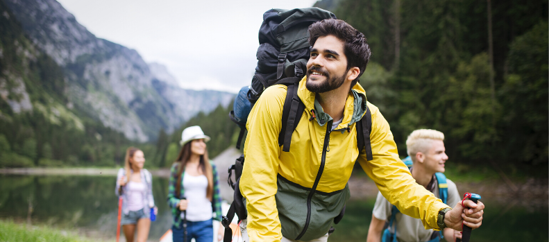 Group of young friends hiking in countryside. Multiracial happy people traveling in nature
