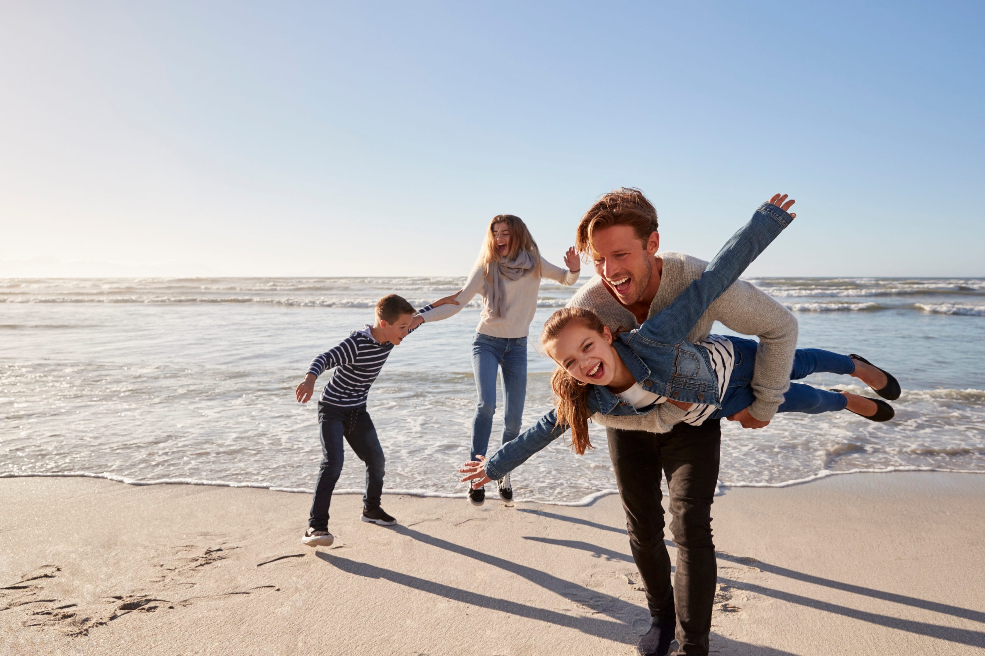 Parents with children having fun on winter beach together